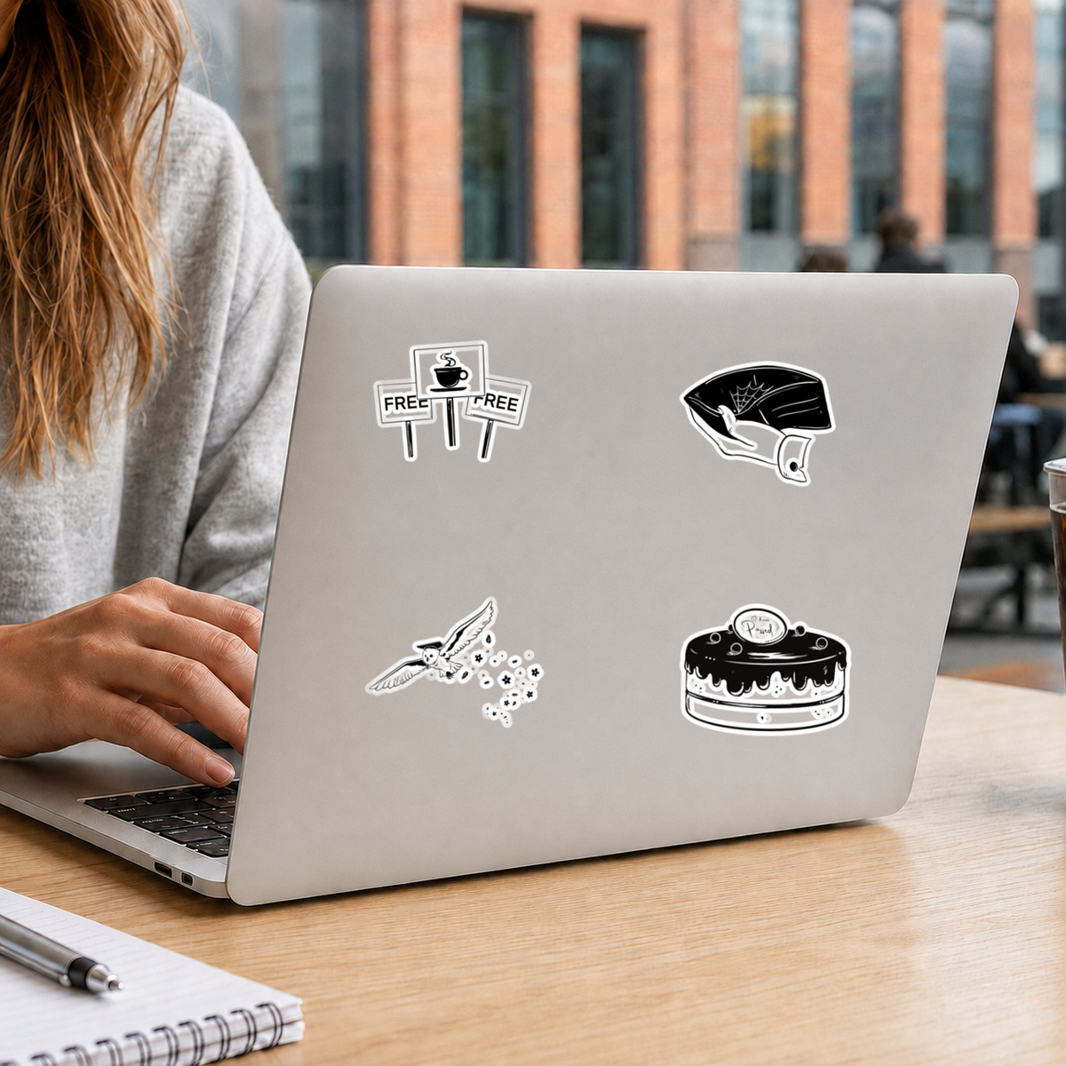 Student gebruikt een laptop met vier zwart-witte studentenstickers op een campus